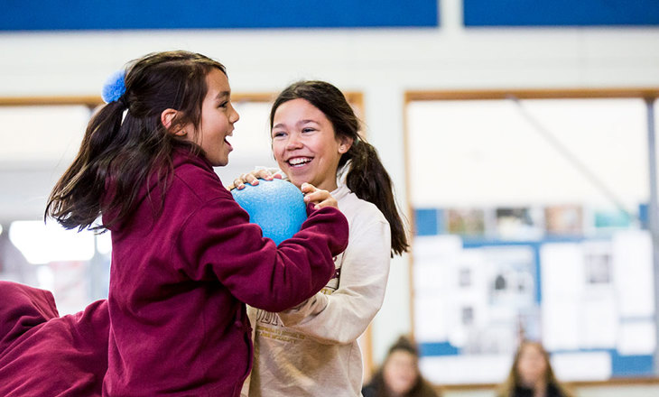 Two students battle to get control of a big blue ball