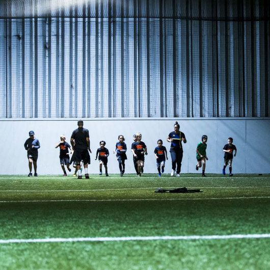 Boys and coaches warming up at an indoor sports facility