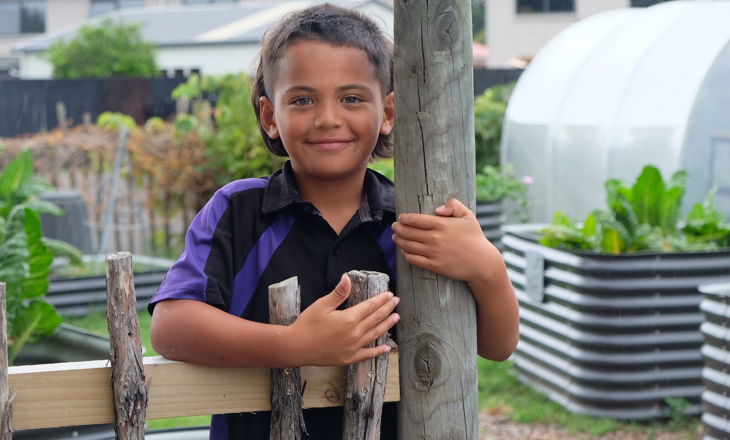 Tamariki looking to camera standing in a garden
