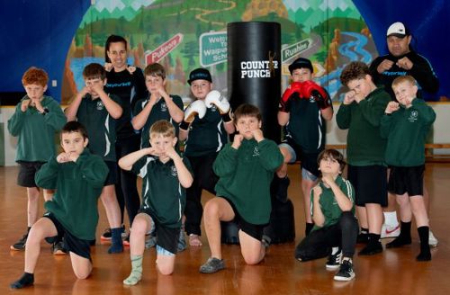 Young school boys in a boxing pose alongside instructors