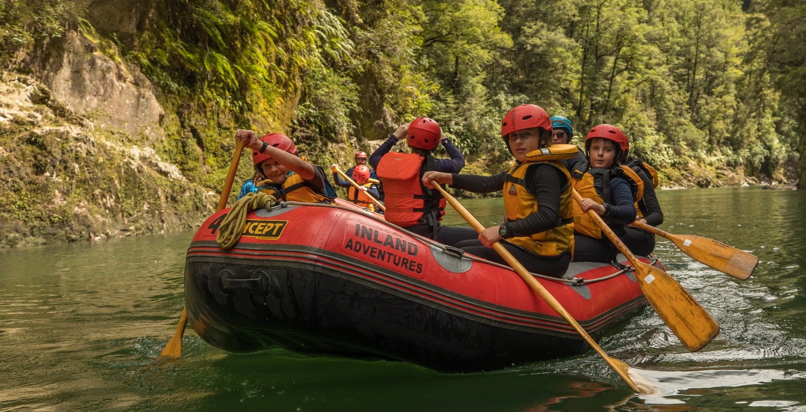 Group of rangatahi paddling along a river