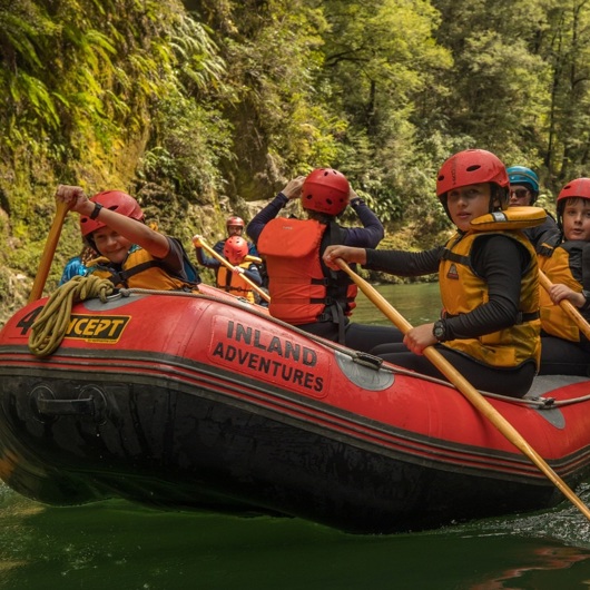 Group of rangatahi paddling along a river