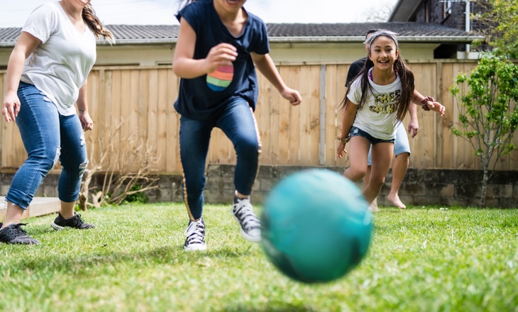 Tamariki running to the ball in the backyard