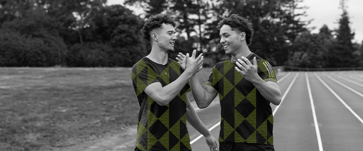 Two rangatahi shaking hands on a running track