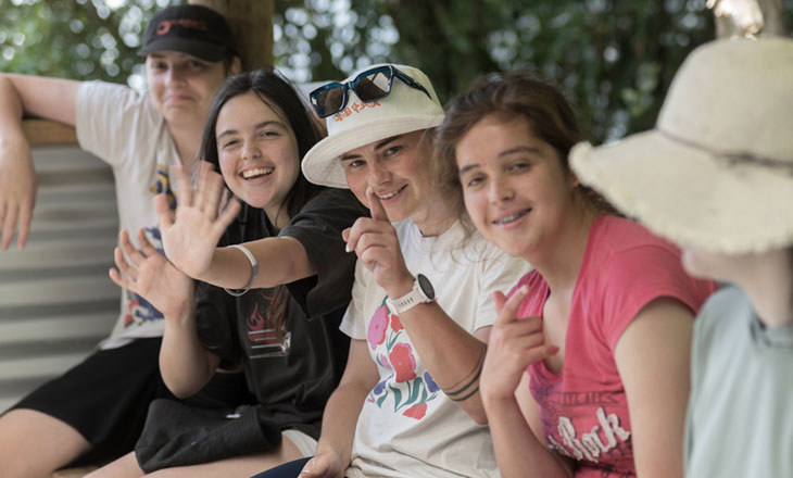 A group of girls smiling and waving at the camera