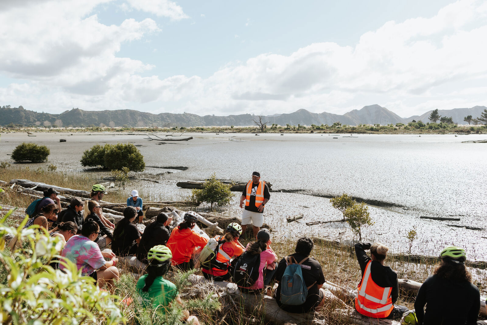 Group sitting next to a coast listening to a teacher