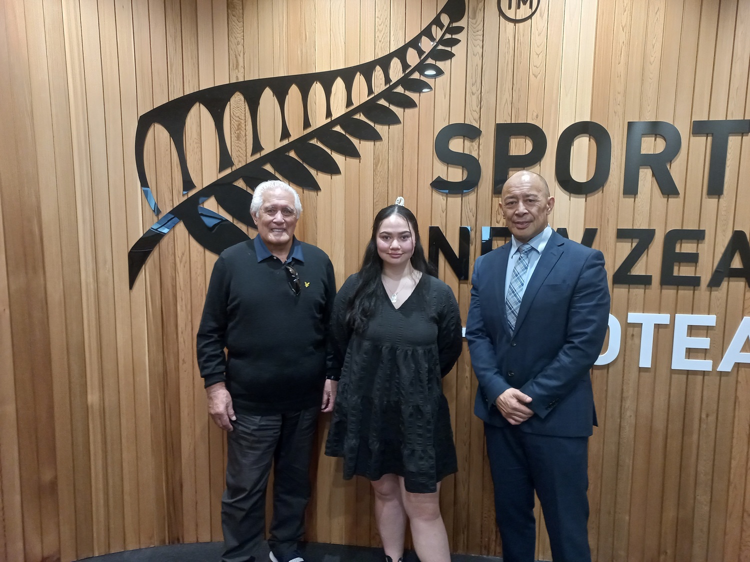 Three people standing in front of the Sport NZ logo