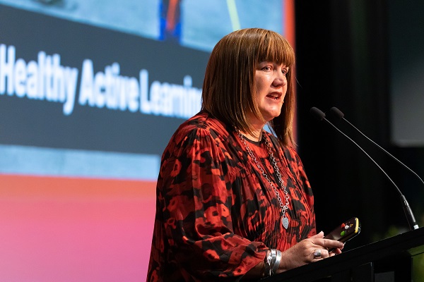 Raelene Castle standing at a podium