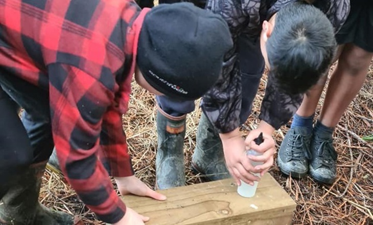 four boys leaning over a wooden box