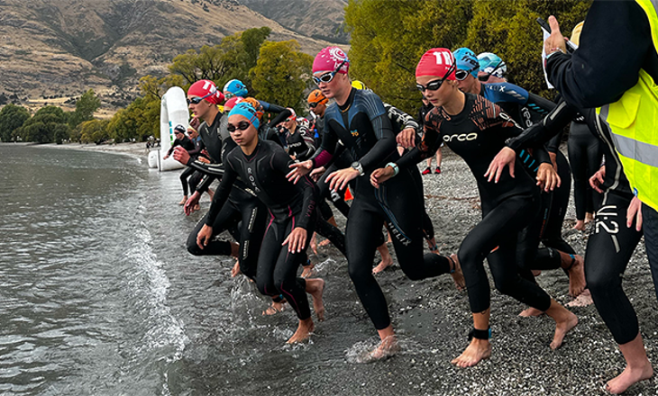 Group in wetsuits running to the ocean