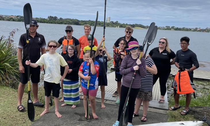 Tamariki holding canoe paddles smiling to camera